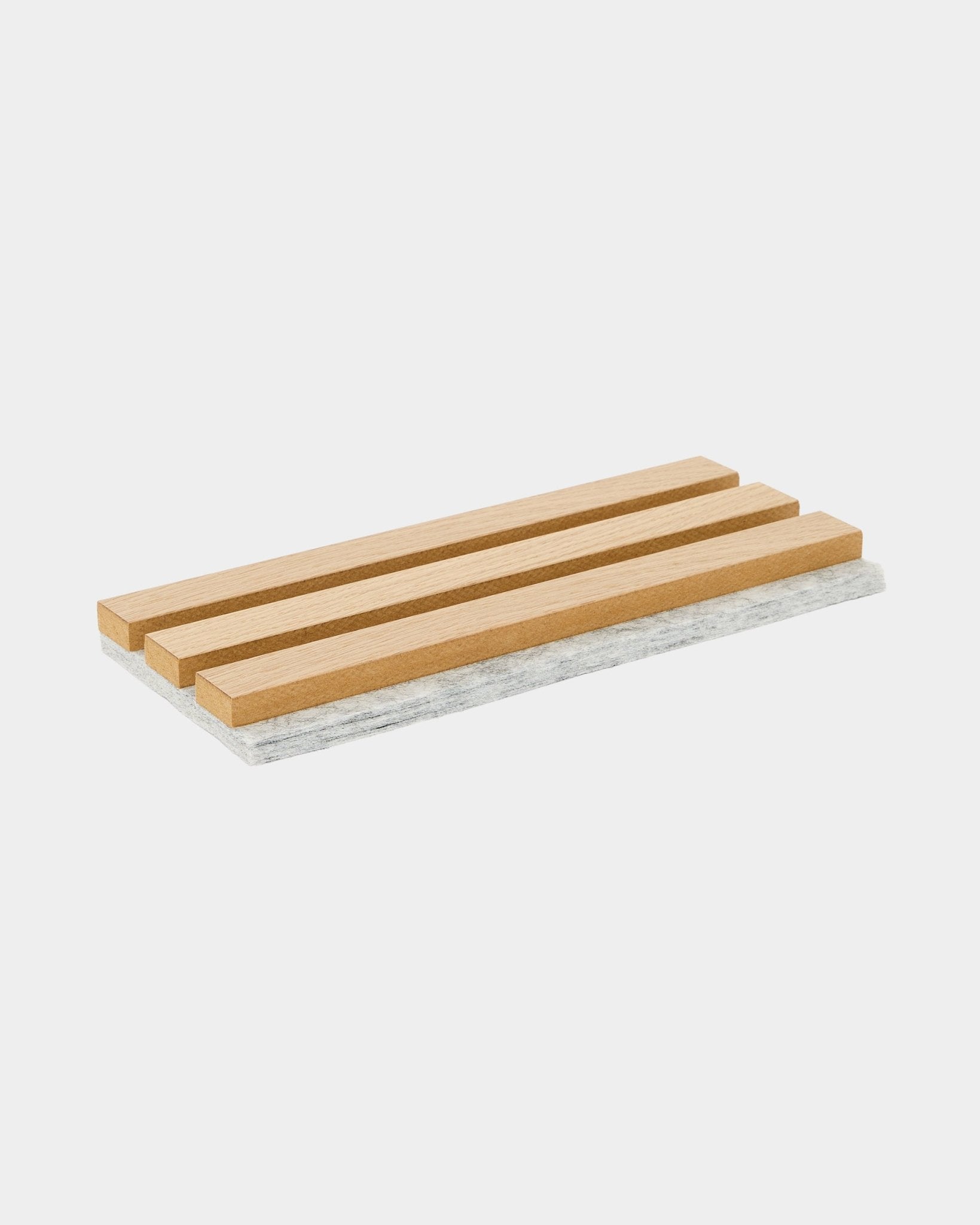 Dessous de plat d’échantillon WoodUpp Akupanel avec des lattes en chêne classique et un support en feutre gris, conçu pour protéger les surfaces et mettre en valeur le matériau acoustique nordique.